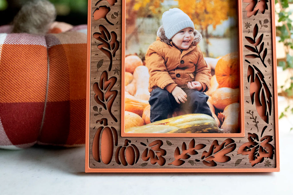 Close-up of the walnut wood inlay on a terracotta Fall Picture Frame, with cut-out autumn leaves and pumpkin designs