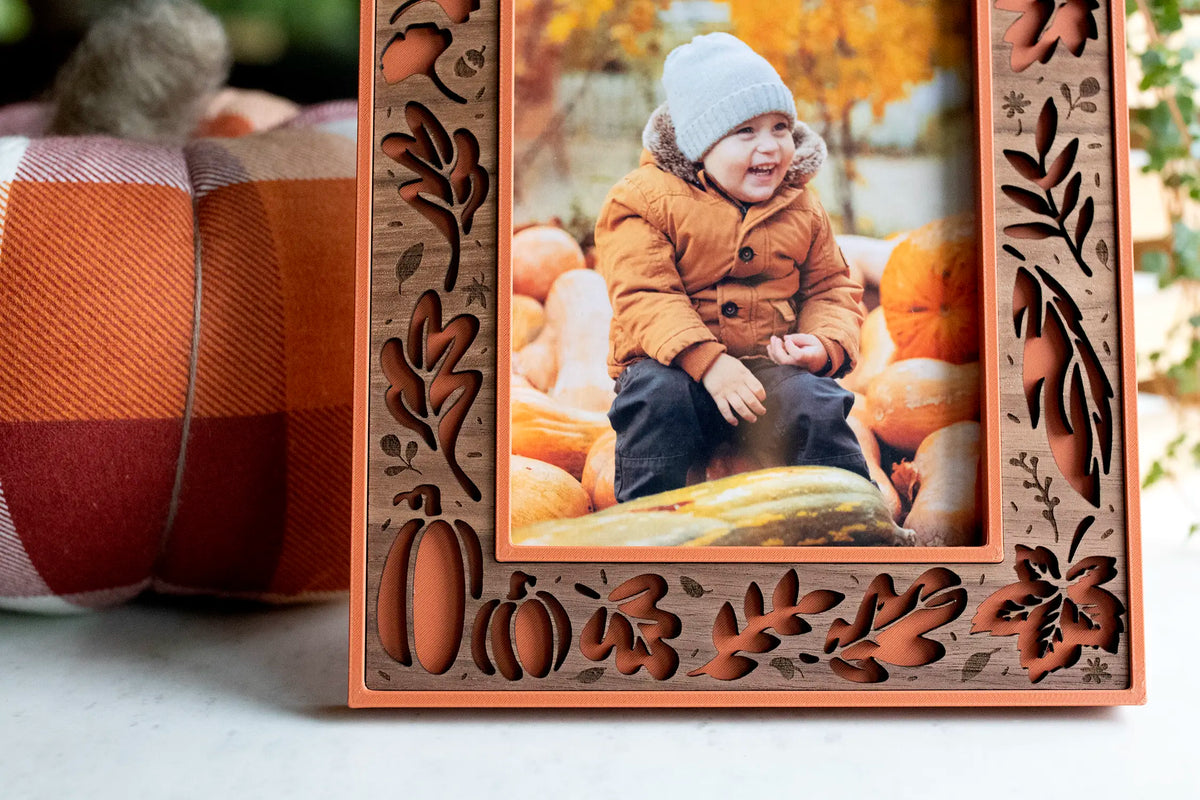 Close-up of the walnut wood inlay on a terracotta Fall Picture Frame, with cut-out autumn leaves and pumpkin designs